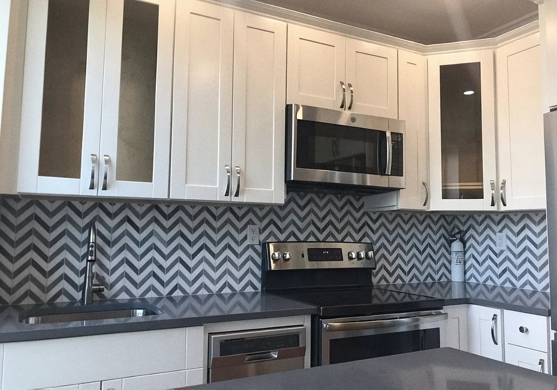 Kitchen after the remodel, with white cabinets and a chevron backsplash