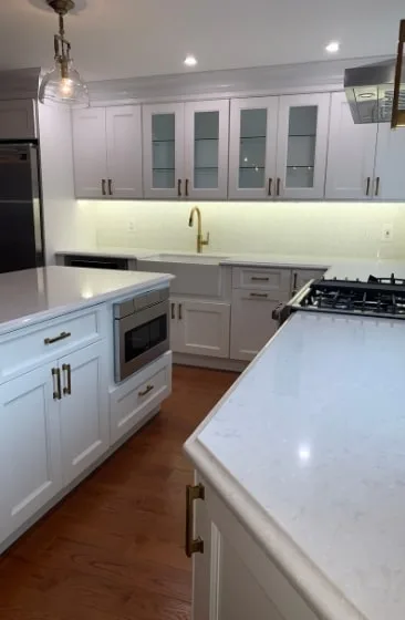 Kitchen counter run with glass-front cabinets and a brass faucet